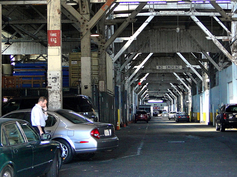 This image depicts an industrial garage located in San Francisco, during the night. The garage is currently unoccupied and appears to be abandoned. There are several cars parked inside, under street lights that illuminate the otherwise dimly lit space. DSC08596.JPG