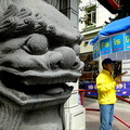 Vendor Standing Near a Statue in Chinatown, San Francisco