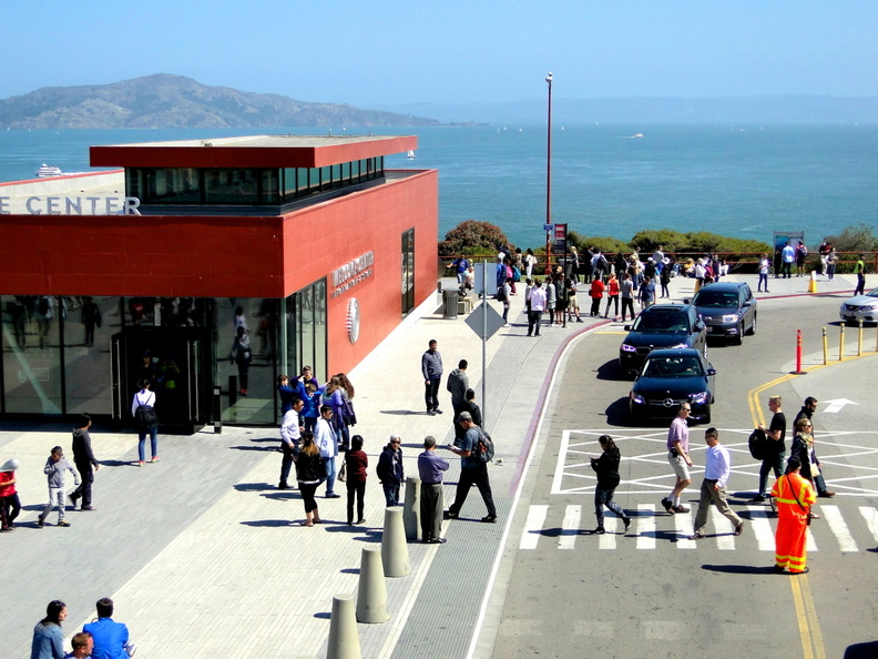 This image captures a vibrant scene at the San Francisco Waterfront Promenade, showcasing a bustling area with various activities. The promenade is filled with pedestrians, some of whom are walking around while others seem to be taking a break on the benches. The presence of numerous people indicates that this location is popular for both locals and tourists alike. In the background, there's a large body of water, suggesting that this area may have a view of the bay or ocean. The image also includes an iconic red tram car, which is synonymous with San Francisco and adds to the overall charm of the scene. The architectural style of the building in the background further emphasizes the urban environment. DSC09142.JPG