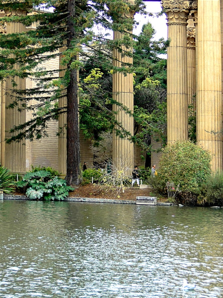 This image captures the peaceful and historic atmosphere of the Greek Amphitheater Park in San Francisco. The park is characterized by its classical design elements, including the ancient columns that form part of the amphitheater's structure. The pond in the center of the park adds a natural element to the urban setting, offering a serene environment for visitors to enjoy. The park appears to be well-maintained with lush greenery around, providing a vibrant contrast to the historical architecture. The scene is completed by a few people enjoying their time near the pond, adding a touch of life to this tranquil setting. DSC09836.JPG