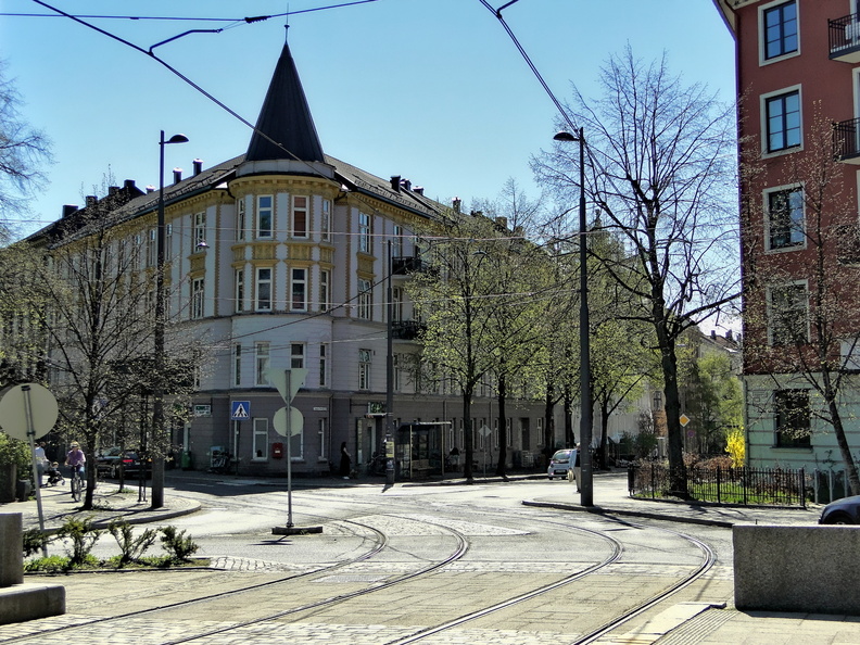 A picturesque view of the tram intersection in Oslo, showcasing a historic building with a distinctive roof and lush greenery surrounding the area. DSC00909.JPG