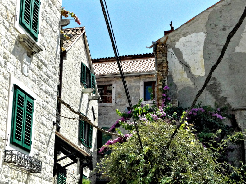 This image captures a charming scene in Split, Croatia. The street corner is lined with quaint buildings featuring vibrant purple flowers blooming on the balconies. The architecture exhibits traditional Mediterranean styles, and the street is quiet and peaceful. This picturesque location invites visitors to explore the rich history and local culture of this European city. DSC01879.JPG