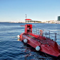 Red Underwater Vehicle at Dock, Cityscape Background