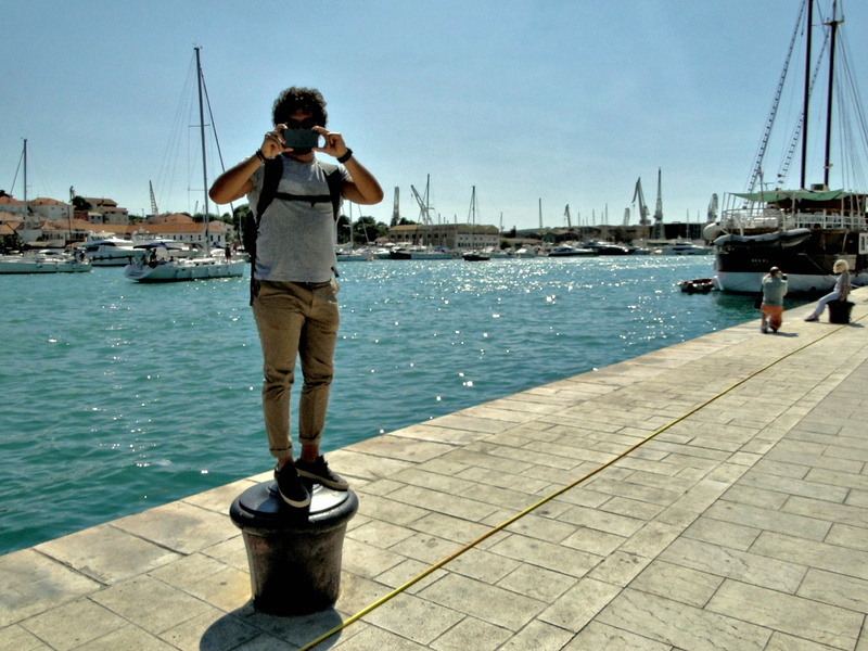 A Tourist on a Dock Overlooking Boats and the Sea