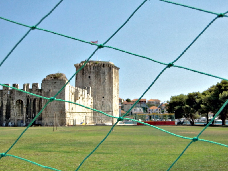 Historical Trogir Fortress Overlooking a Sports Field with Net Fencing