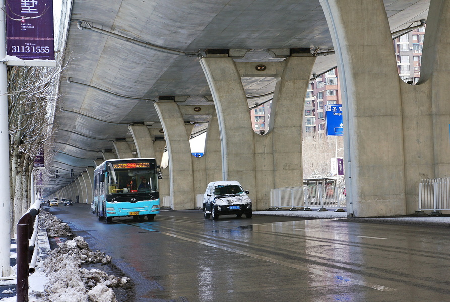 Rainy Day in Shenyang: A Bus Makes Its Way Under an Overpass