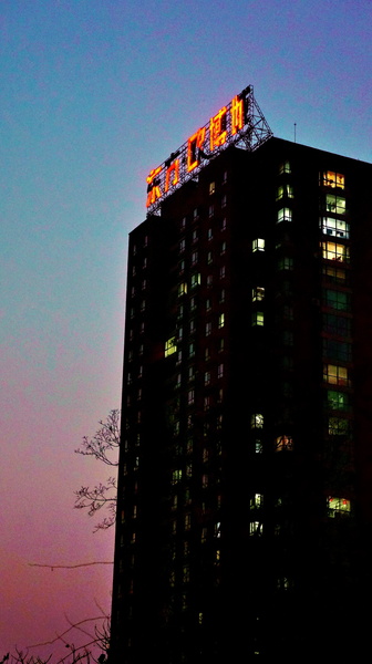 A Nighttime View of a Tall Building with a Sign in Shenyang, China