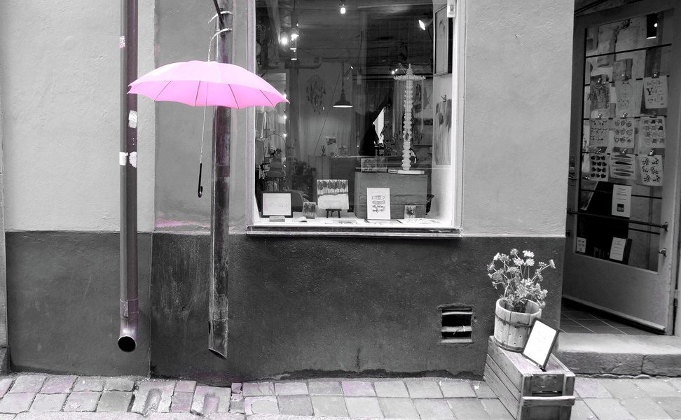Stockholm Chic: A Pink Umbrella Enhances a Modern Storefront on a Rainy Day