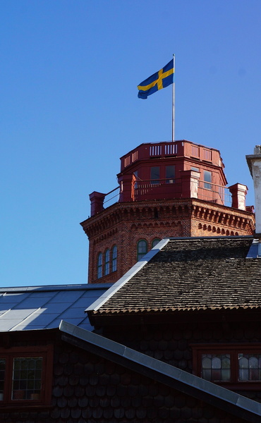The Swedish Flag atop a historic red building, viewed through an overlay of the same flag