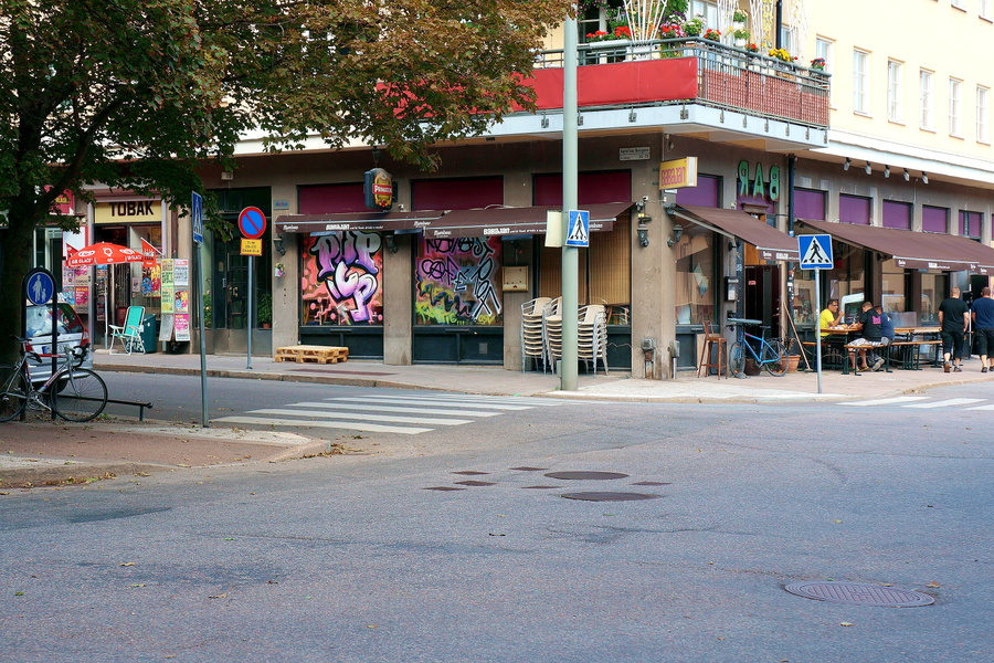 An empty intersection in a European city, with graffiti on a building.