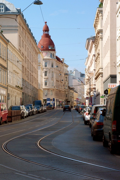 A tranquil Vienna street lined with parked cars and trolley tracks.