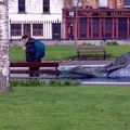 A Lone Traveler Admiring a City Statue and Fountain