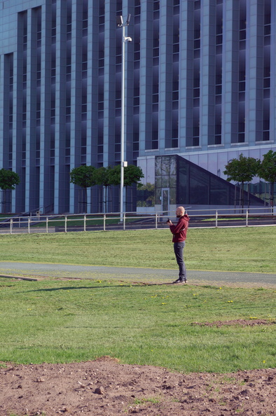 An Individual Standing in an Open Area with a Building in the Background