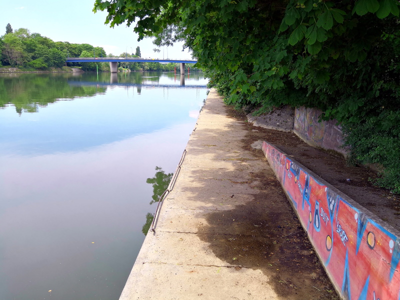 Serene Riverside Walkway with Colorful Graffiti and Mural