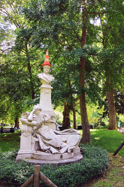Ancient Sculpture in Park with Orange Cone