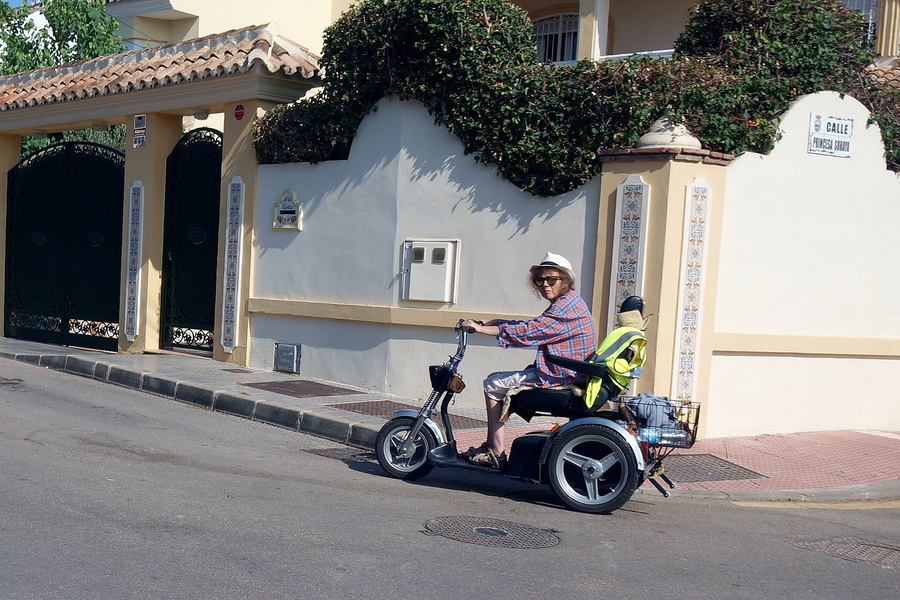 Elderly Man Rides Scooter in European Residential Area