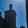 Sunlit Riga Street Scene with Clock Tower and Power Lines
