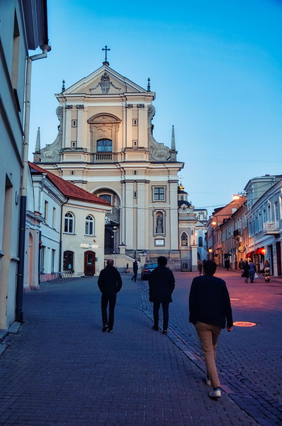 A serene night walk in Vilnius, Lithuania, past a grand church.