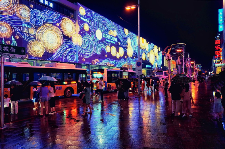 A Vibrant Night in Shenyang, China: Lights and People Amidst a Rainstorm