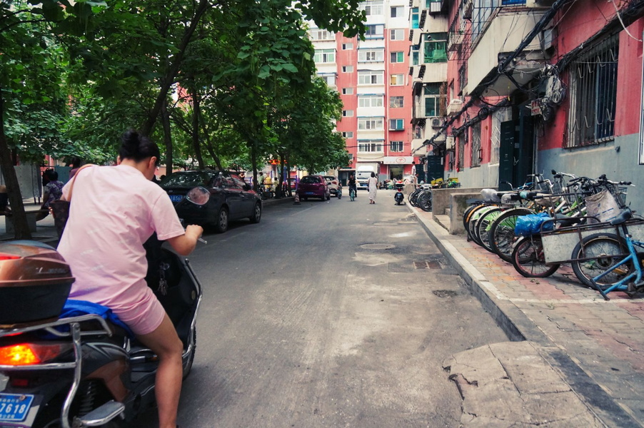 Vibrant City Life in China: A Man Rides a Scooter Through the Streets