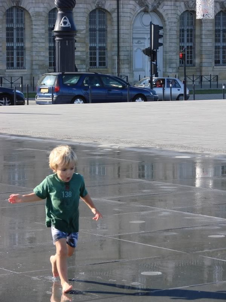 A Little Boy Walking in the Rain on a City Street