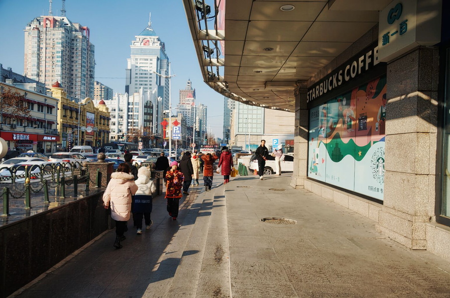 Vibrant City Life in Harbin, China: A Pedestrian Walkway Enveloped by Skyscrapers and a Coffee Shop