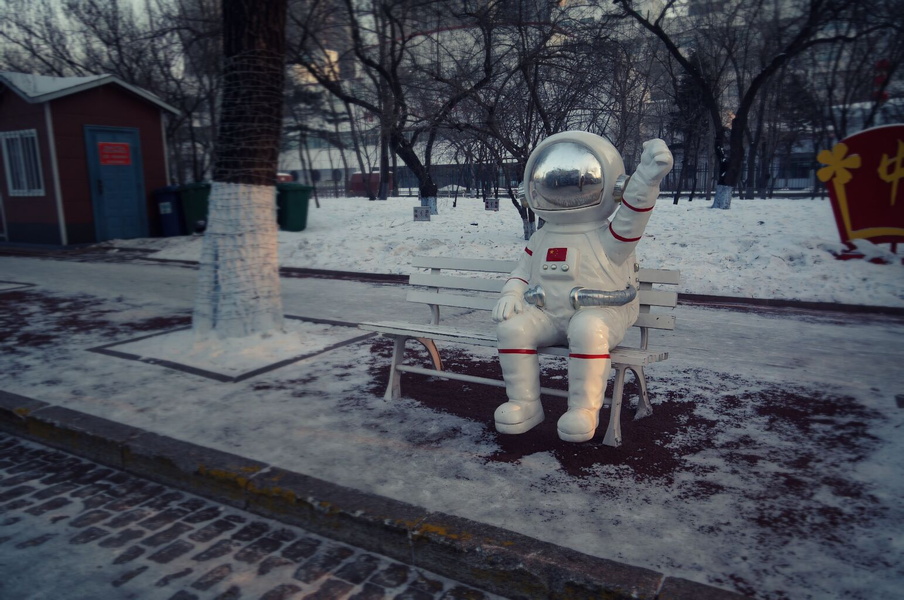 A Space Suit Sculpture Enjoys a Bench on a Snowy Day in Harbin, China