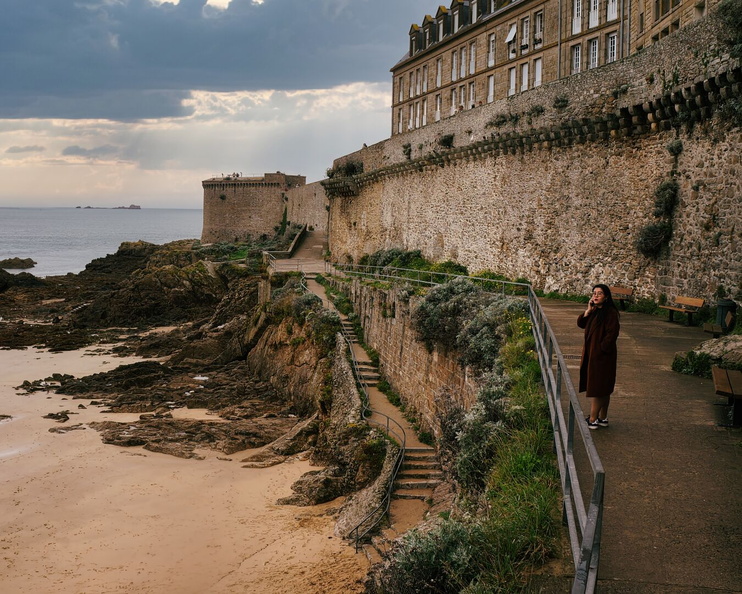 Lone Wanderer Contemplates the Ocean Amidst Historic Walls