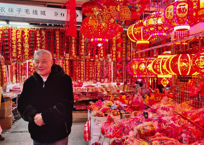 A man stands amidst a vibrant display of Chinese lanterns and gifts.