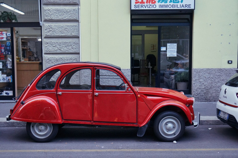 An Antique Red Car Parked on a Milanese Street
